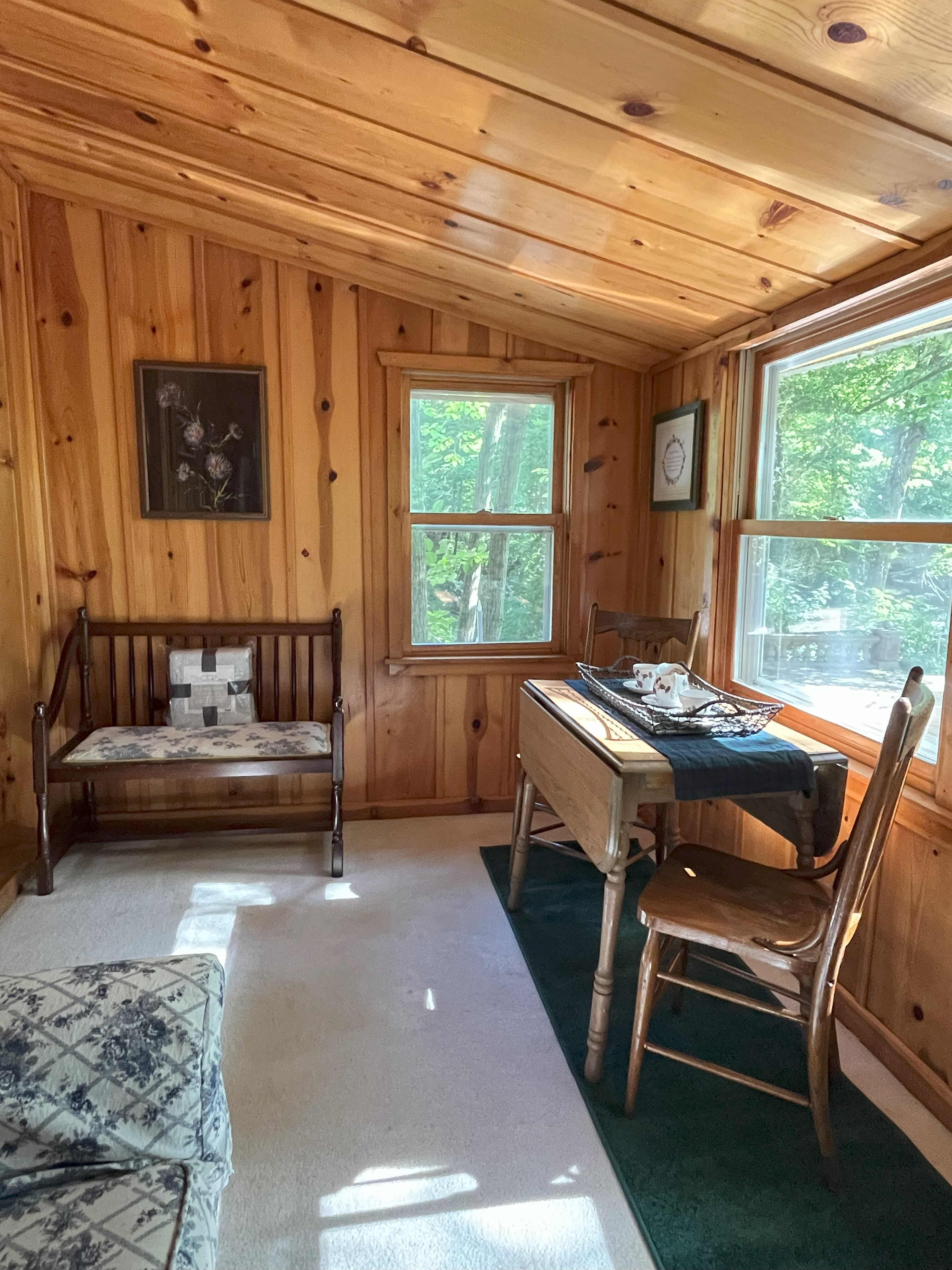Sunroom dining area with knotty pine walls and creek views